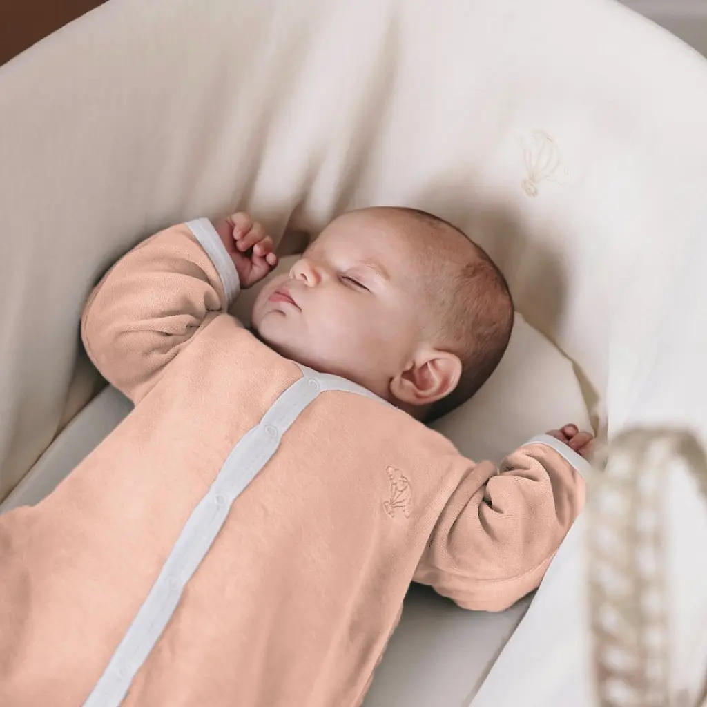 Bébé endormi sur le dos dans un couffin, une alternative sûre au réducteur de lit