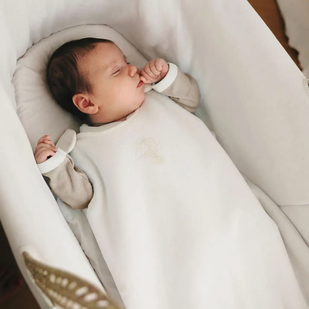 Bébé endormi dans sa gigoteuse en coton bio, couché sur le dos dans un couffin